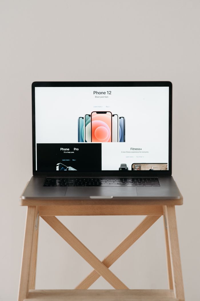about-img A sleek laptop on a wooden table showing a smartphone advertisement, perfect for tech and gadget content.